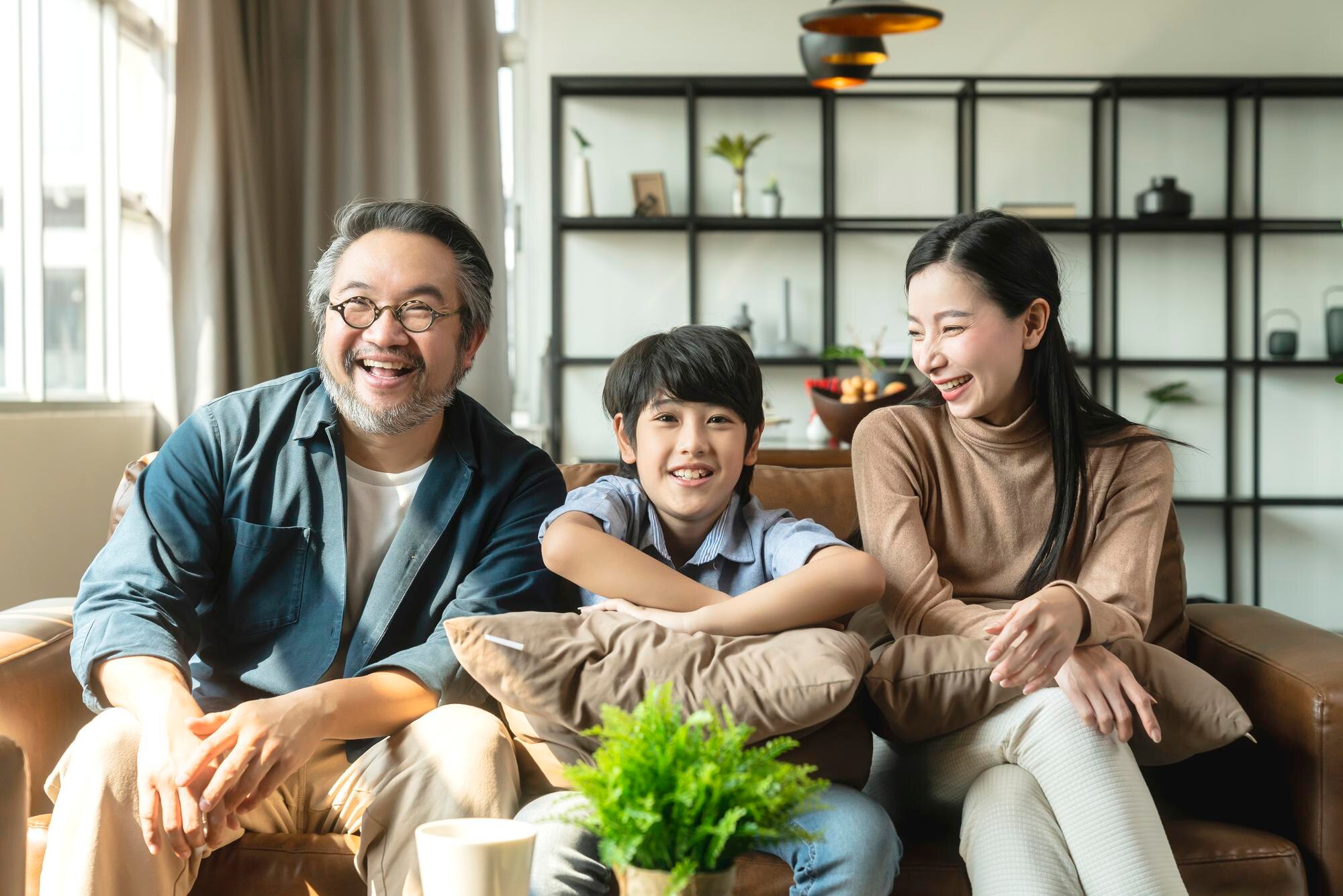 happy-cheerful-asian-family-parent-with-child-boy-son-watching-tv-together-spending-holiday-weekend-time-quarantine-sofa-living-room-family-home-concept_609648-4